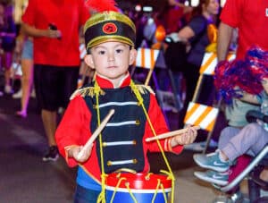 A cute photo of a little drummer boy at an event.