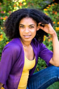 An outdoor headshot of an African American woman in a garden.