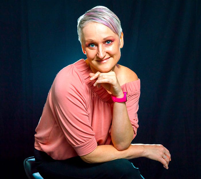 A headshot picture of a woman in front of a black background.